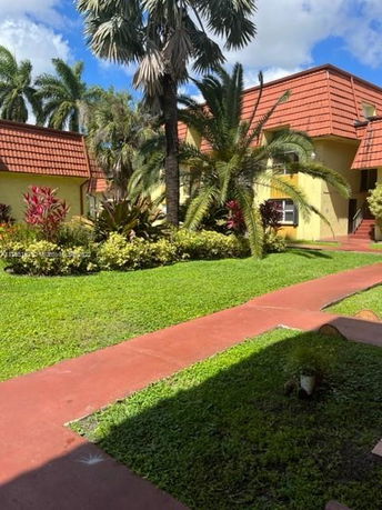 Front view of a house with a red-tiled roof and yellow exterior walls.