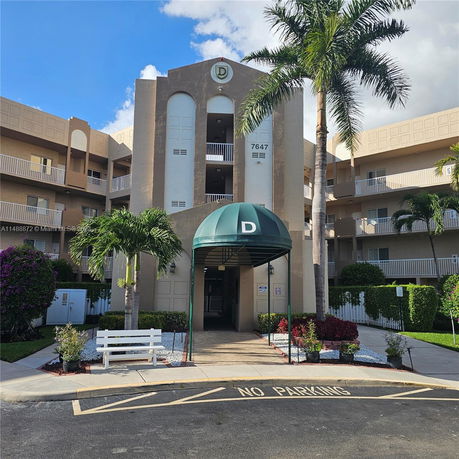 Front view of a multi-story building with a central entrance and green awning.