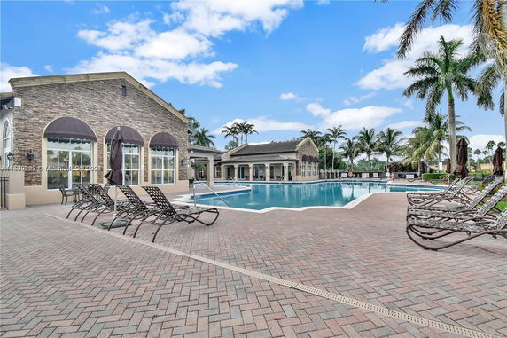 Outdoor swimming pool area with lounge chairs and a building with arched windows.