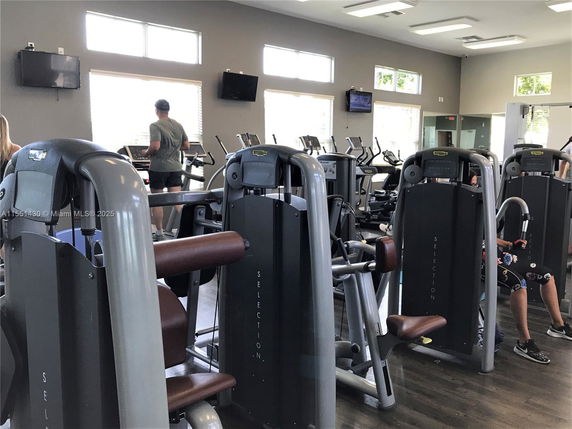 Indoor gym area with exercise machines and individuals working out.