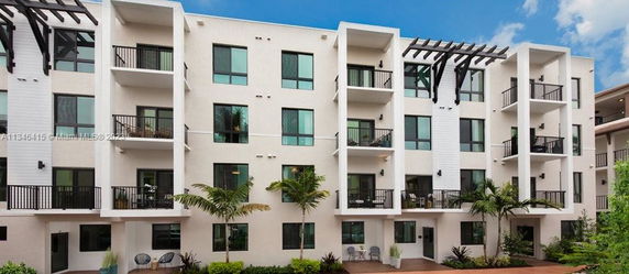 Front view of a modern four-story apartment building with balconies.