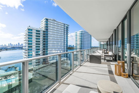 Panoramic view from a modern building balcony overlooking water and other buildings.
