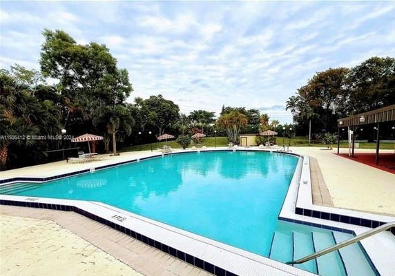 Outdoor swimming pool area with surrounding greenery.