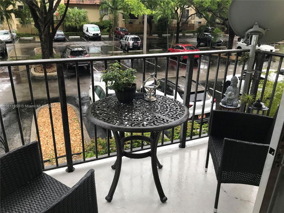 View from a balcony overlooking a parking area with cars under rain.