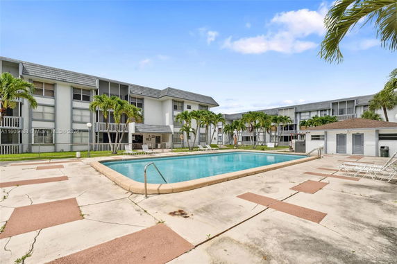 Outdoor swimming pool in front of a multi-story residential building.