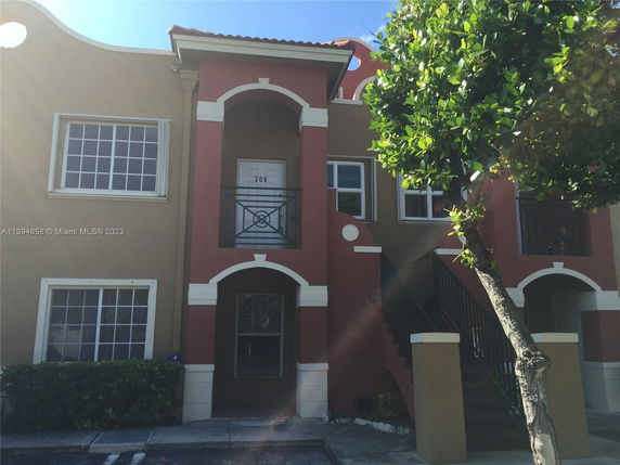 Front view of a two-story residential building with arched balconies and a staircase entrance.