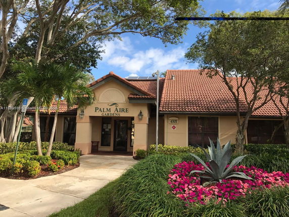 Front view of a building with a tiled roof and a front entrance labeled 'Palm Aire Gardens.'