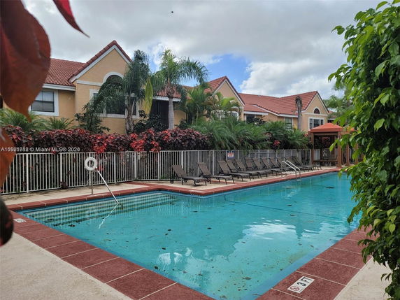 Outdoor swimming pool area with sun loungers and surrounding residential buildings.