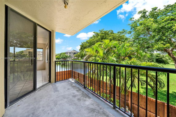 View from a building balcony overlooking greenery and nearby structures.