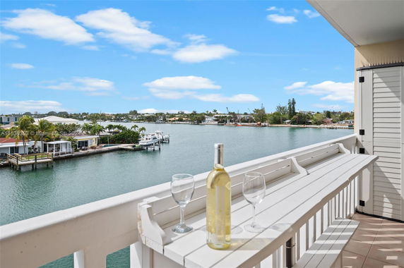Panoramic view from balcony overlooking waterway and houses with boats.