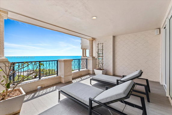 Balcony with lounge chairs and ornate railing, overlooking the ocean.