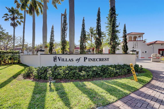 Entrance view of Villas of Pinecrest with surrounding palm trees.