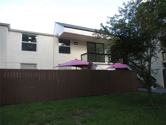 Front view of a multi-story house with a balcony and fenced patio.