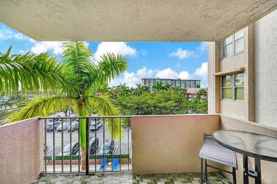 View from a balcony overlooking a parking area and distant buildings.