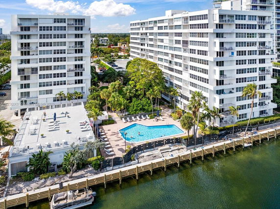 Aerial view of a residential complex with a swimming pool by the waterfront.