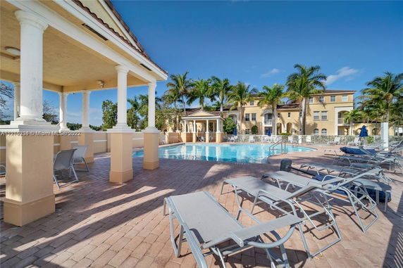 Outdoor swimming pool area with lounge chairs and covered seating.