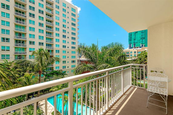 View of multiple high-rise buildings and palm trees from a balcony.