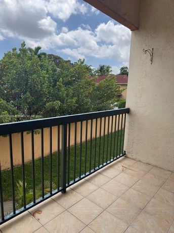 View from a balcony overlooking a landscaped area with trees.