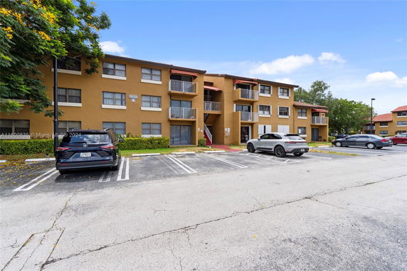 Parking area in front of a three-story residential building with balconies.