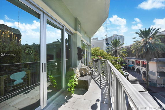 View from a balcony overlooking surrounding buildings and palm trees.