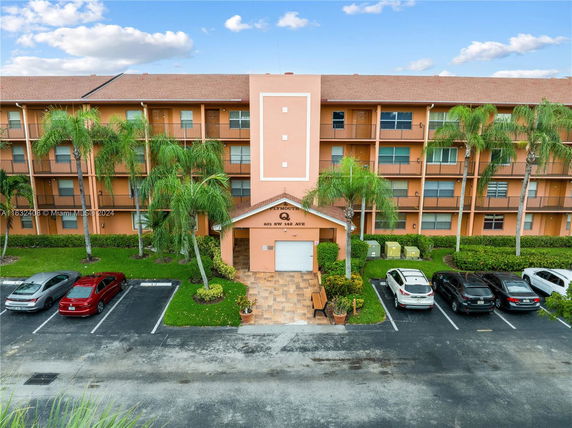 Front view of a multi-story residential building with parking area.