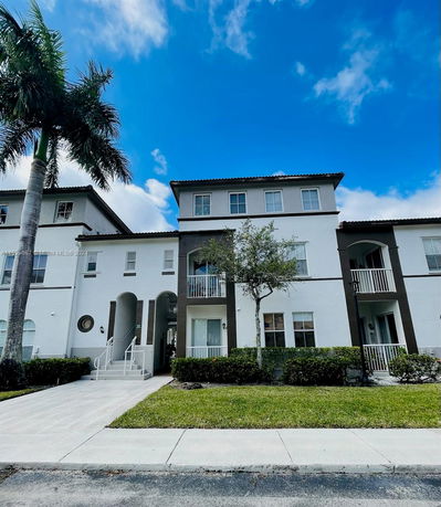 Front view of a multi-story residential building with balconies and a small staircase.