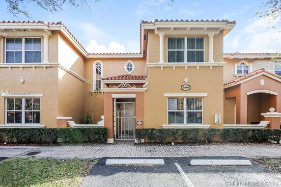 Front view of a two-story townhouse with a gated entrance and tiled roof.