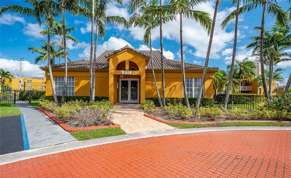 Front view of a yellow building with a tiled roof and entrance steps.