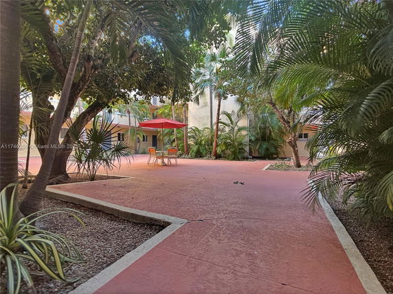 Outdoor view of a courtyard with a patio area and red umbrella.