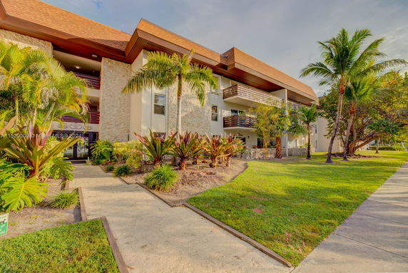 Front view of a multi-story building with balconies and landscaped surroundings.