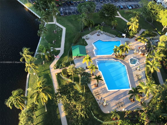 Aerial view of a rooftop area with a large swimming pool, surrounded by trees and pathways.