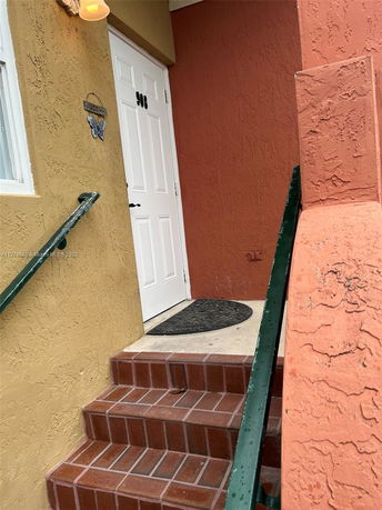 Entrance of a house with a white door and brick steps.