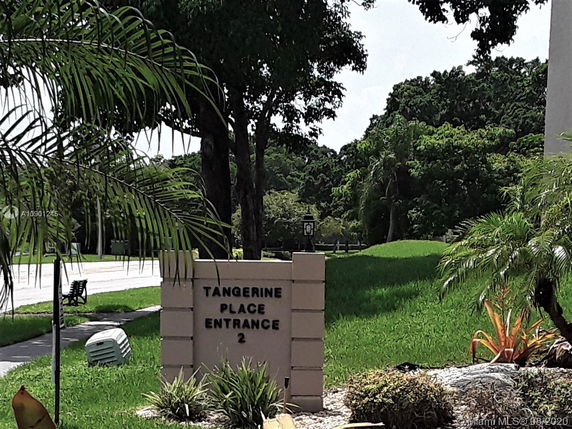 Entrance sign for Tangerine Place with surrounding greenery.