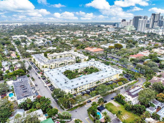 Aerial view of a residential area with apartment complexes and city skyline in the background.