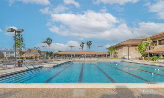 Outdoor swimming pool with surrounding seating and tropical landscaping.