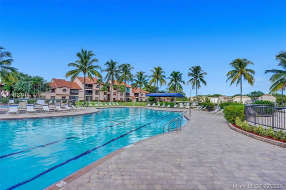 Outdoor view of a large swimming pool with lounge chairs and a building in the background.