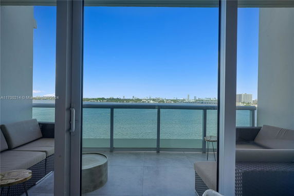 Panoramic view from a balcony overlooking a body of water and a distant city skyline.