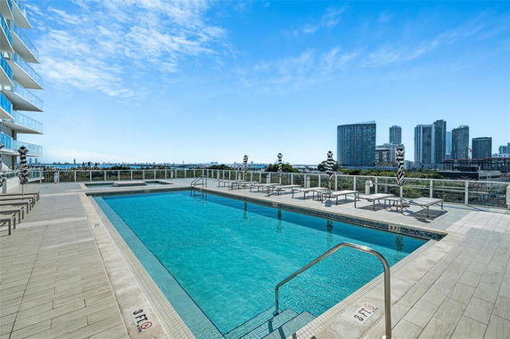 Outdoor swimming pool on a rooftop with city skyline in the background.