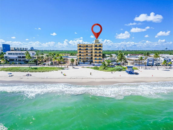 Aerial view of a multi-story beachfront building with surrounding beach and ocean.