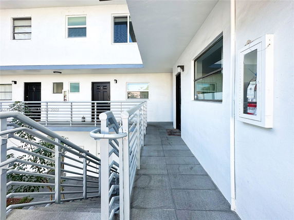 Front view of a building entrance with stairs leading to doors and windows on an upper level.