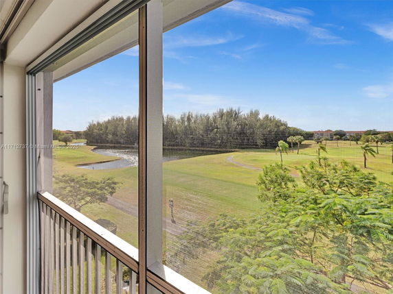 View from a balcony overlooking a grassy field and a pond.