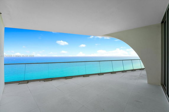 Spacious balcony with glass railing overlooking the ocean.