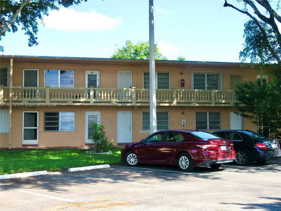 Front view of a two-story building with a parking area in front.