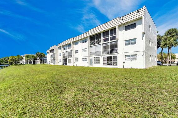 Front view of a three-story residential building with white exterior and enclosed balconies.