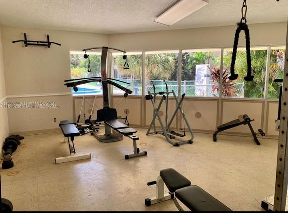 Room with gym equipment including weight benches and exercise machines.