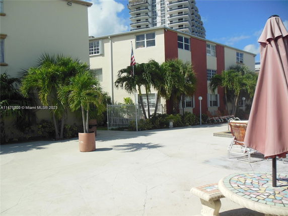 View of a multi-story building with palm trees and outdoor seating area in the foreground.