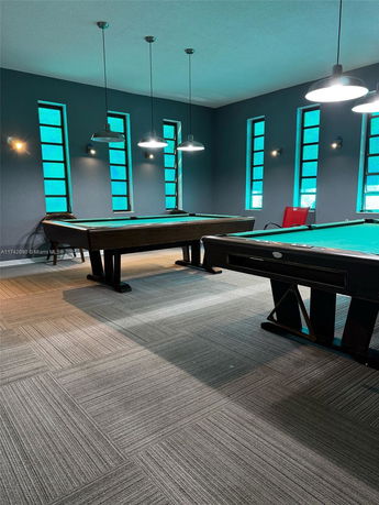 Interior view of a recreation room with pool tables and modern lighting.