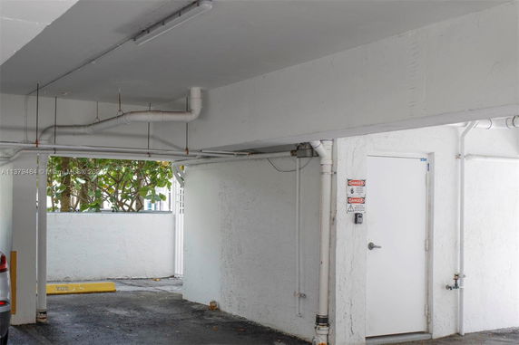 Covered parking area with a view of a wall and a door.