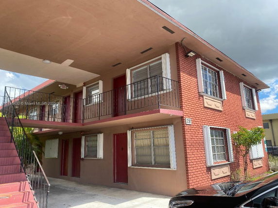 Front view of a two-story residential building with brick exterior and metal railings.