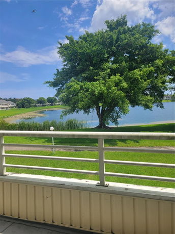 View of a lake and tree from a balcony on a sunny day.